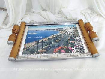 Datant des années 60, voici un plateau en bois clair serti par endroits de parties métalliques avec une vue de Nice, sa  Promenade des Anglais et l’Hôtel Négresco et recouvert d'une vitre aux décors miroir avec l'écusson de la Cote d’Azur.