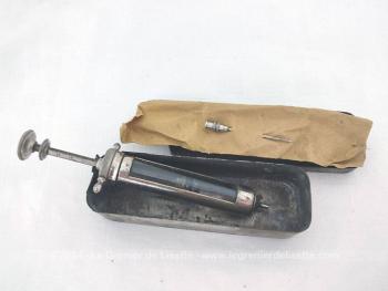 Voici une ancienne seringue en verre, sa grande aiguille et sa boite en métal usée et élimée par le temps.