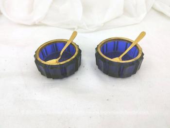 Voici un ensemble salière et poivrière en verre couleur bleu cobalt, habillé de laiton au col et deux petites cuillères en métal doré .