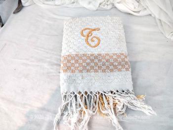 Sur un fond blanc, voici une ancienne serviette de toilette en éponge fine sur 62 x100 cm, décorée d'un damier moutarde à chaque extrémité et brodée d'un grand T  majuscule (dans le style calligraphie).