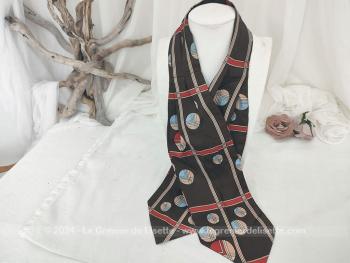 Voici un foulard forme Ascot vintage en polyester dans des coloris très tendance seventeen avec sur fond marron des cercles et raies rouges, marron et beiges, sur 122 cm de long et 15 cm de large aux extrémités.