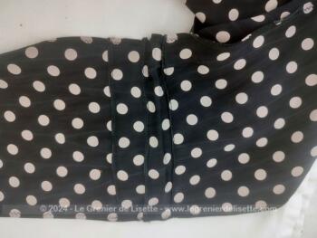 En polyester imitation soie, voici une belle lavallière noire à pois blancs décorée de petits plis religieuses avec une extrémité en biais et une droite, de 200 x 16 cm pour un joli noeud autour du cou, d'un chapeau ou autres idées.