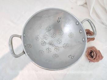 Sur 22.5 cm de diamètre, voici une ancienne passoire tripode en aluminium avec des trous pour égoutter en forme de rond et estampillée sur l'extérieur d'un pied  