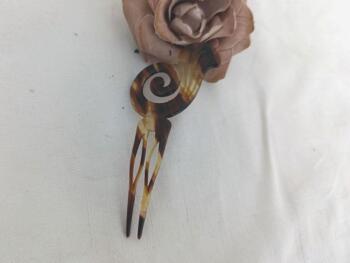 Sur 12 x 5.5 x0.2 cm, voici un superbe ancien peigne à chignon à deux dents, datant surement des années 40/50 et réalisé en rhodoïd imitation corne et portant une estampille presque illisible.