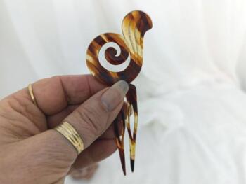 Sur 12 x 5.5 x0.2 cm, voici un superbe ancien peigne à chignon à deux dents, datant surement des années 40/50 et réalisé en rhodoïd imitation corne et portant une estampille presque illisible.