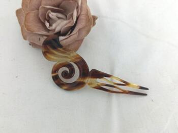 Sur 12 x 5.5 x0.2 cm, voici un superbe ancien peigne à chignon à deux dents, datant surement des années 40/50 et réalisé en rhodoïd imitation corne et portant une estampille presque illisible.