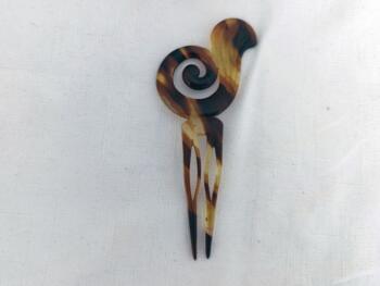 Sur 12 x 5.5 x0.2 cm, voici un superbe ancien peigne à chignon à deux dents, datant surement des années 40/50 et réalisé en rhodoïd imitation corne et portant une estampille presque illisible.