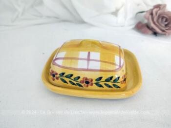 Voici un petit beurrier en céramique sur fond jaune en deux parties, avec sur le couvercle cadrillage et une guirlande de fleurs. Estampillé 