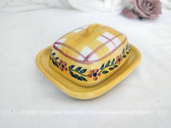 Voici un petit beurrier en céramique sur fond jaune en deux parties, avec sur le couvercle cadrillage et une guirlande de fleurs. Estampillé 