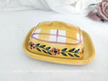 Voici un petit beurrier en céramique sur fond jaune en deux parties, avec sur le couvercle cadrillage et une guirlande de fleurs. Estampillé 