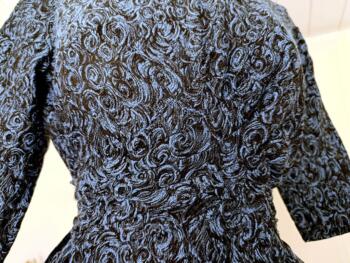 Fait main, voici une élégante robe vintage en tissus épais bleu chiné  fermée par une fermeture éclair et décorée par deux liens pour former une ceinture avec un grand et large pan qui tombe sur un coté. Taille 38  totalement dans l'air des années 50/60.