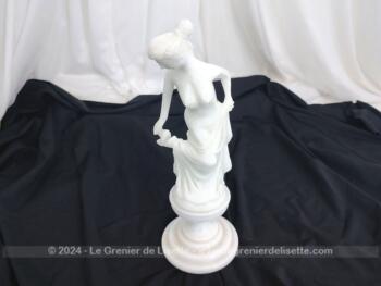 Voici une belle statuette, sculpture en albâtre blanc d'une jeune femme dévêtue, son vêtement glissant le long de ses jambes et tenant sa chaussure.  Superbe !