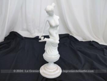 Voici une belle statuette, sculpture en albâtre blanc d'une jeune femme dévêtue, son vêtement glissant le long de ses jambes et tenant sa chaussure.  Superbe !