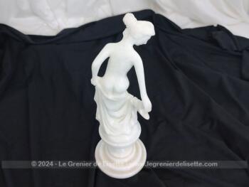 Voici une belle statuette, sculpture en albâtre blanc d'une jeune femme dévêtue, son vêtement glissant le long de ses jambes et tenant sa chaussure.  Superbe !