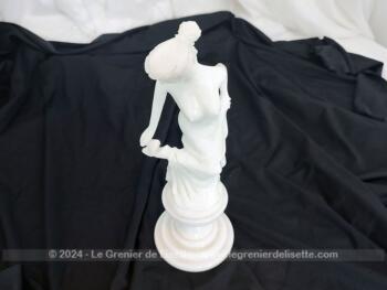 Voici une belle statuette, sculpture en albâtre blanc d'une jeune femme dévêtue, son vêtement glissant le long de ses jambes et tenant sa chaussure.  Superbe !
