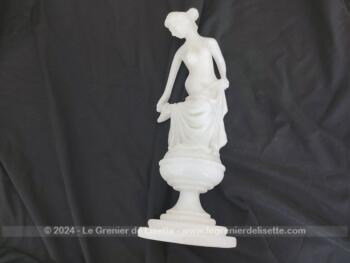 Voici une belle statuette, sculpture en albâtre blanc d'une jeune femme dévêtue, son vêtement glissant le long de ses jambes et tenant sa chaussure.  Superbe !