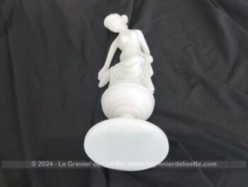 Voici une belle statuette, sculpture en albâtre blanc d'une jeune femme dévêtue, son vêtement glissant le long de ses jambes et tenant sa chaussure.  Superbe !