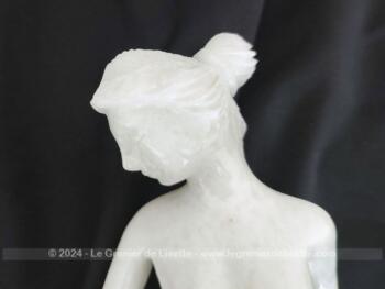 Voici une belle statuette, sculpture en albâtre blanc d'une jeune femme dévêtue, son vêtement glissant le long de ses jambes et tenant sa chaussure.  Superbe !