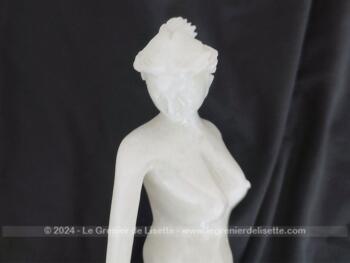 Voici une belle statuette, sculpture en albâtre blanc d'une jeune femme dévêtue, son vêtement glissant le long de ses jambes et tenant sa chaussure.  Superbe !