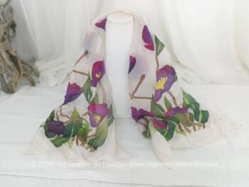 Sur 40 x 140 cm, voici une belle écharpe en soie naturelle ivoire avec aux deux extrémités de larges décors de fleurs peintes à la main dans des tons de mauve, jaune et verts et portant une signature.