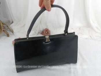 Voici un sac vintage en cuir vernis noir avec une poche intérieure simple et une fermée par une fermeture éclair. Il se ferme par un fermoir à clapet. Sa anse lui permet de le porter à la main, au bras et même à l'épaule. Top vintage !