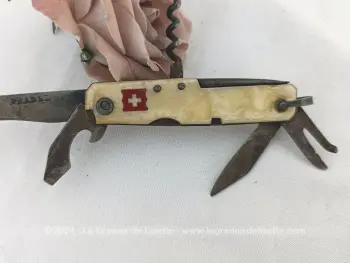 Habillage bakélite imitation nacre avec de petits manques, voici ancien petit couteau Suisse vintage avec ses 6 petits outils ou ustensiles bien patinés par le temps. Drapeau Suisse sur le manche.