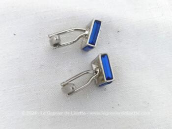 Voici une paire de boutons de manchettes vintages représentant un carré de verre couleur bleu cobalt serti dans un habillage de métal argenté.