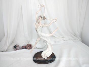 Sur 50 cm de haut et 40 cm de large et posée sur un socle en bois, voici une belle statuette en résine, représentant une danseuse exécutant un grand jeté mettant en valeur le voile de sa robe et celui de son étole. Superbe !
