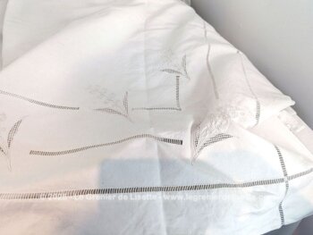 Coupon d'un ancien grand drap de lin de 205 x 320 cm avec un revers sublime composé d'un quadrillage de jours, des broderies , des broderies ajourées et des monogrammes incompréhensibles. Pièce unique.