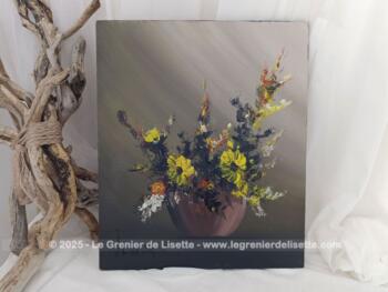 Sur 33.5 x 40 cm,  voici un bien original tableau réalisé en peinture à l'huile sur bois représentant sur un fond couleur taupe, une bouquet de fleurs à dominante jaune dans un vase posé sur un socle. Une signature visible semble indiquer 