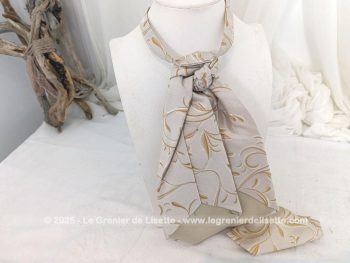 Voici une belle cravate Ascot à l'allure vintage en tissus 100% polyester beige aux dessins de volutes couleur caramel surlignées d'un liseré brillant avec une pochette assortie.