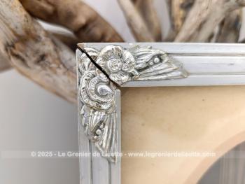 Sur 27 x 21 x 1cm, voici un cadre en bois peint couleur vieil argent  avec des fleurs en reliefs aux angles et  mettant en valeur une photo d'un mariage du début du siècle.  Tout dans ce cadre nous transporte avec nostalgie dans le monde vintage des années 30!