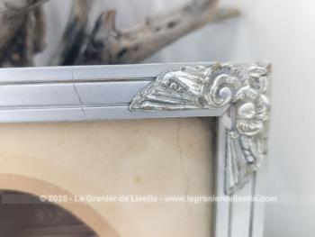 Sur 27 x 21 x 1cm, voici un cadre en bois peint couleur vieil argent  avec des fleurs en reliefs aux angles et  mettant en valeur une photo d'un mariage du début du siècle.  Tout dans ce cadre nous transporte avec nostalgie dans le monde vintage des années 30!