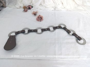 Sur 94 cm de long et 7 cm de large, voici une ceinture vintage, totalement dans le look des années 70 et composée de morceaux d'élastique marron reliant entre eux 7 larges anneaux en métal martelé, dont le dernier sert de fermeture.