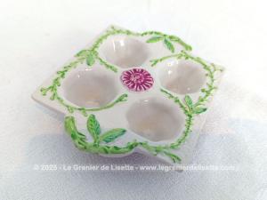 Voici un présentoir vintage pour 4 oeufs en céramique couleur ivoire et décoré de feuillage vert et d'une fleur fuchsia au centre. Au dos, une estampille, un tampon complétement illisible.