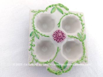 Voici un présentoir vintage pour 4 oeufs en céramique couleur ivoire et décoré de feuillage vert et d'une fleur fuchsia au centre. Au dos, une estampille, un tampon complétement illisible.