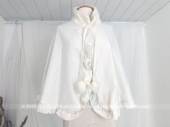 Superbe cape vintage en imitation feutre de laine écrue, son col en imitation fausse fourrure fermée par 2 liens et pompons. 