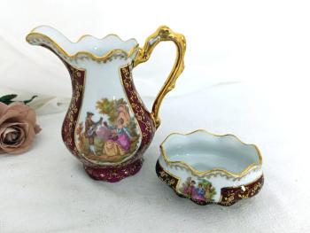 En porcelaine de Limoges Jammet Seignolles, voici un pichet verseur à lait et un sucrier vintages avec des dorures, un fond bordeaux et des écussons avec des dessins style XVIII°.