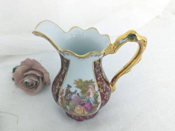 En porcelaine de Limoges Jammet Seignolles, voici un pichet verseur à lait et un sucrier vintages avec des dorures, un fond bordeaux et des écussons avec des dessins style XVIII°.