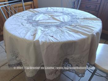 Belle nappe ronde en coton écru de 160 cm de diamètre décorées par de belles broderies simples et ajourées, et habillée par des incrustations de dentelles couleur taupe réalisées au crochet. Superbe.