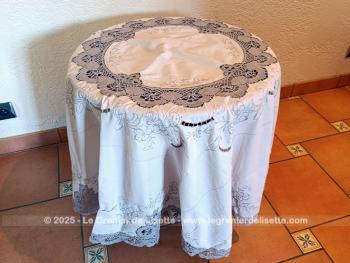 Belle nappe ronde en coton écru de 160 cm de diamètre décorées par de belles broderies simples et ajourées, et habillée par des incrustations de dentelles couleur taupe réalisées au crochet. Superbe.