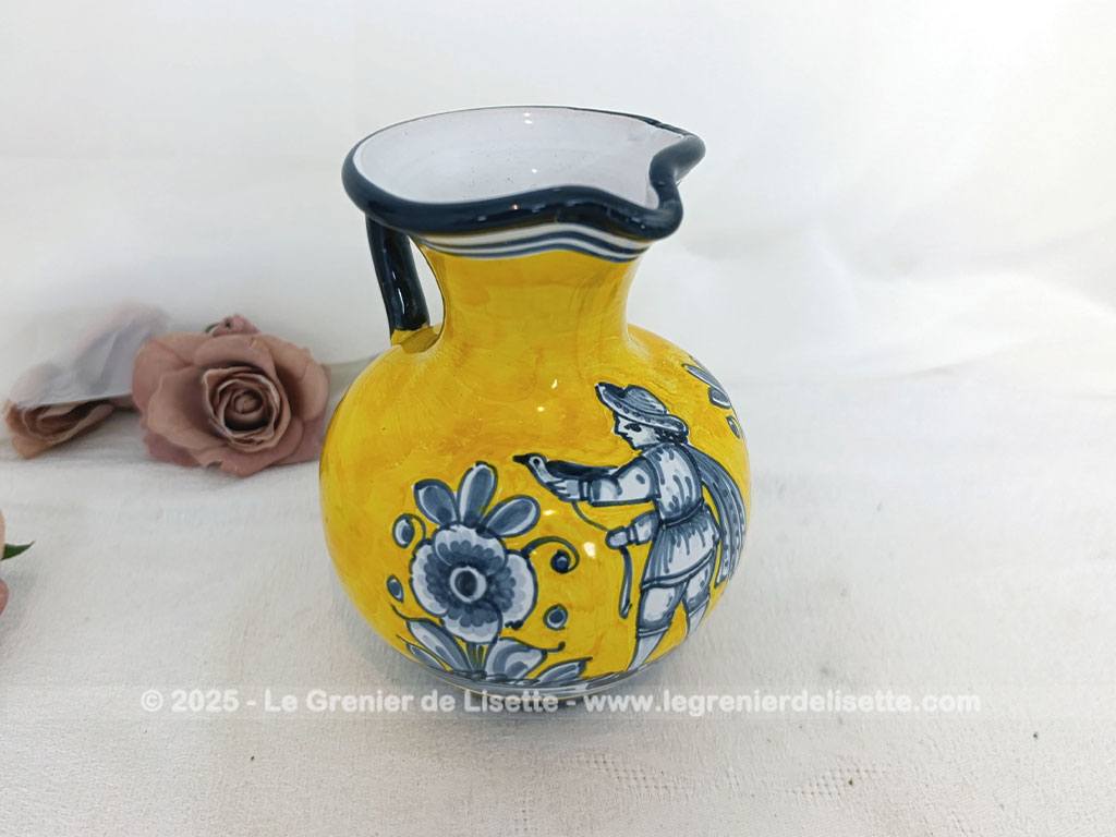 Voici un beau pichet vintage, surement originaire d'Espagne, signé et numéroté, avec sur un fond jaune foncé des décors d'un personnage peint en gris bleu avec des fleurs.