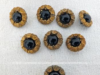 Voici un lot de 8 beaux boutons vintages en  métal doré ouvragés pour une imitation strass et décorés d'une perle noire au centre en plastique.