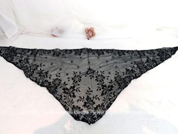 De forme triangulaire, voici une mantille vintage en fine dentelle noire toute en dentelle mécanique avec une belle guirlande de fleurs sur les contours et un grand dessin de bouquet de fleurs sur la partie en pointe. 