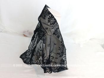 De forme triangulaire, voici une mantille vintage en fine dentelle noire toute en dentelle mécanique avec une belle guirlande de fleurs sur les contours et un grand dessin de bouquet de fleurs sur la partie en pointe. 