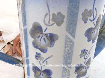 Voici une ancienne cafetière émaillée, sans couvercle mais signée, habillé d'un décor vertical de guirlande et de fleurs, prete à être exposée pour une décoration au charme authentique avec ses éclats.