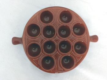 En céramique émaillée brun, voici un plat de présentation avec 12 emplacements et deux poignées, estampillé Emile Henry France  25 - 12. Idéal pour escargots, oeufs  ou autres idées culinaires de décoration.