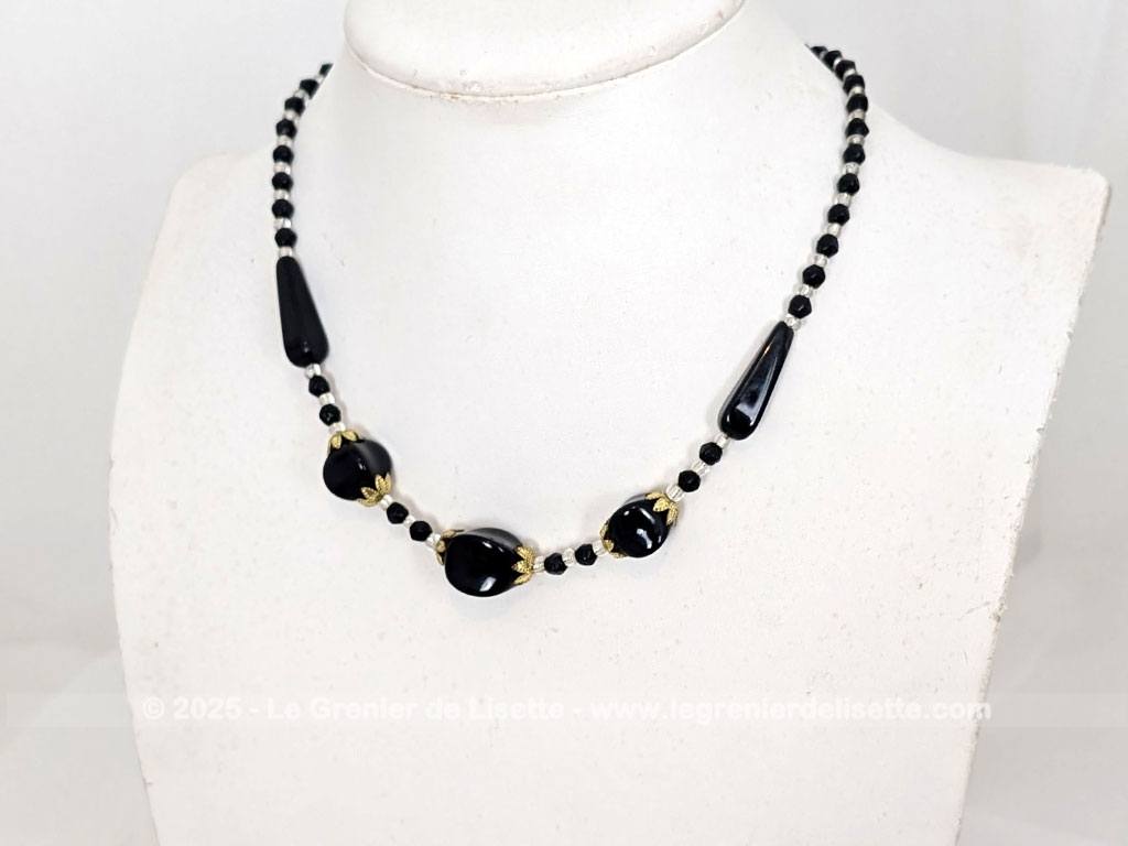 Superbe collier ras de cou réalisé avec d'une part une composition de grandes perles en verre noir, habillées de coupelles en métal doré et de petites perles noires et translucides. Pour un décolleté très élégant.
