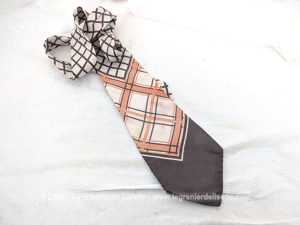 Voici une belle cravate vintage des années 70 de la marque Jean Patou en soie écrue et décorée de formes géométriques couleur chocolat et oranges.Doublure soie également estampillée Jean Patou.