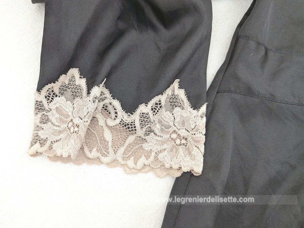 Elégant déshabillé en veste courte d'intérieur polyester, polyamide et élastane noire et décoré de large dentelle écrue.Marque